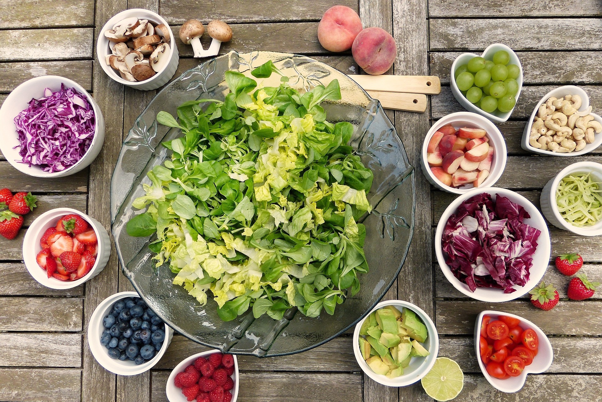Eine große Salatschüssel und viele kleine Schüsseln mit Obst & Gemüse.